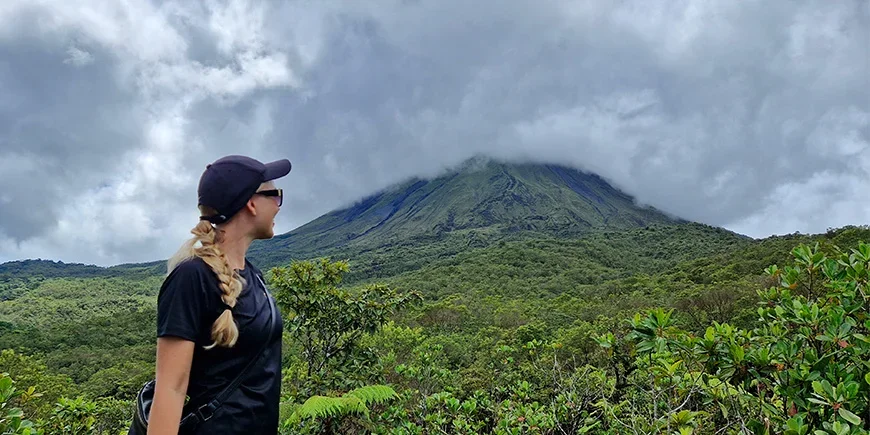 Nadia från TourCompass framför Arenalvulkanen en molnig dag i Costa Rica