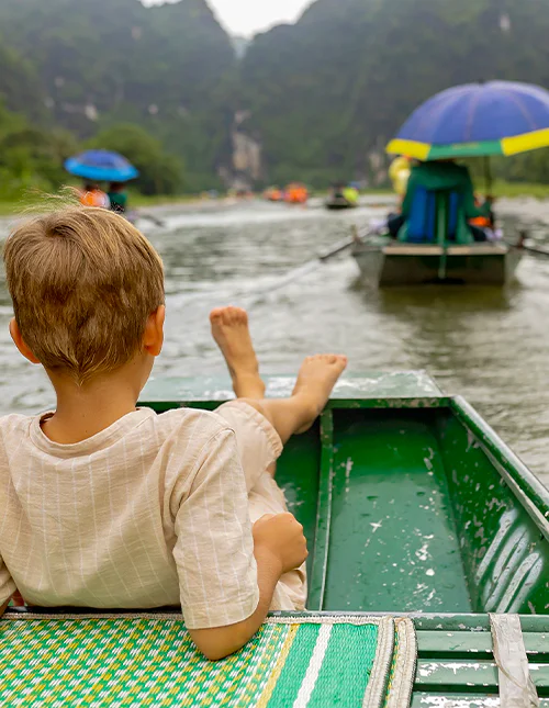Ett barn njuter av en båttur i Ninh Binh, Vietnam
