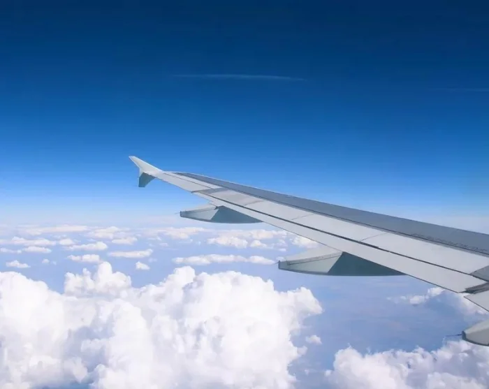 Flygvinge över molnen på väg till resmålet