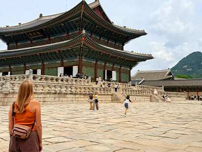 En kvinna står och tittar på Gyeongbokgungpalatset i Seoul