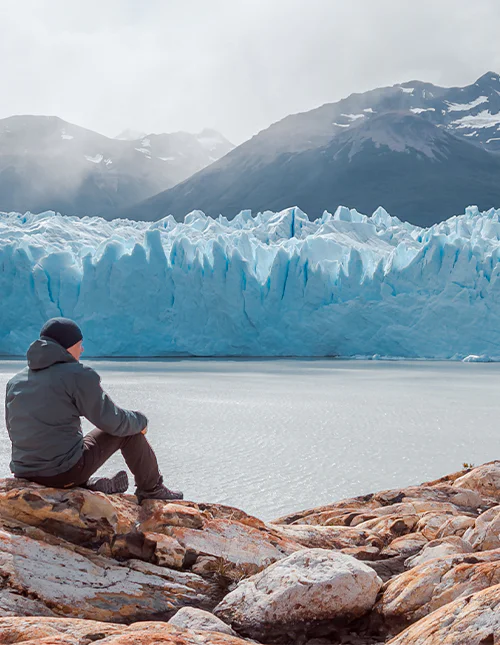 Man sitter framför glaciären Perito Moreno i nationalparken Los Glaciares