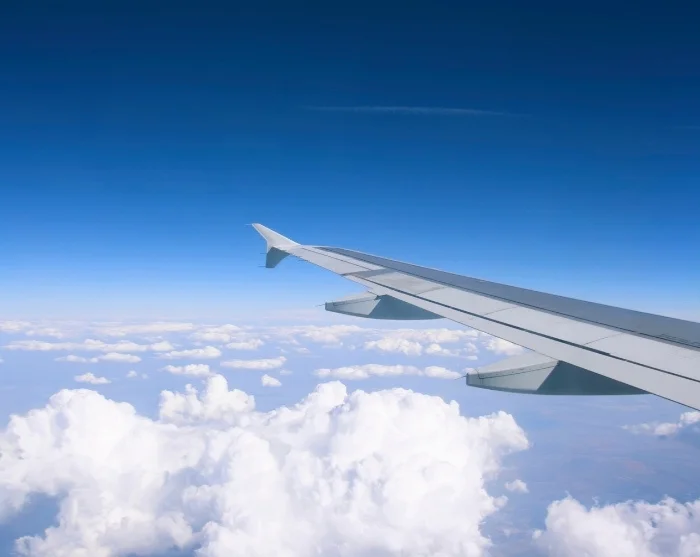 Flygvinge över molnen på väg till resmålet