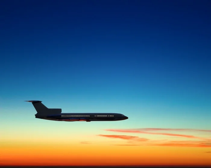 Flyg på himlen i solnedgången