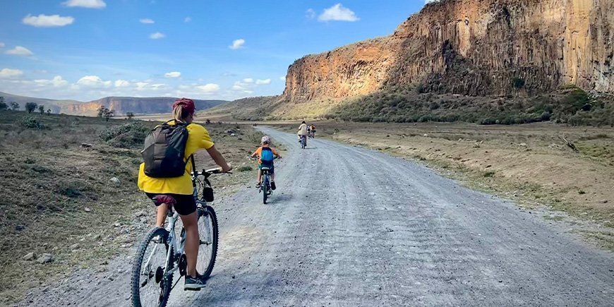 Kvinna och familj cyklar i Hells Gate nationalpark i Kenya.