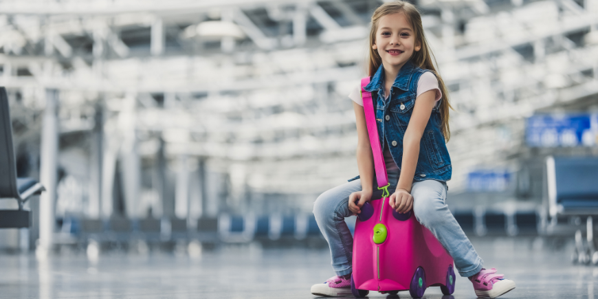 Barn sitter på en resväska på en flygplats 
