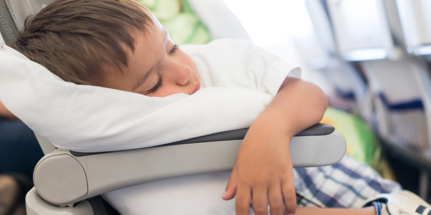 Pojke sover med kudde på flyget