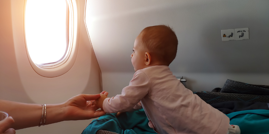 Liten bebis ser ut genom flygplansfönstret