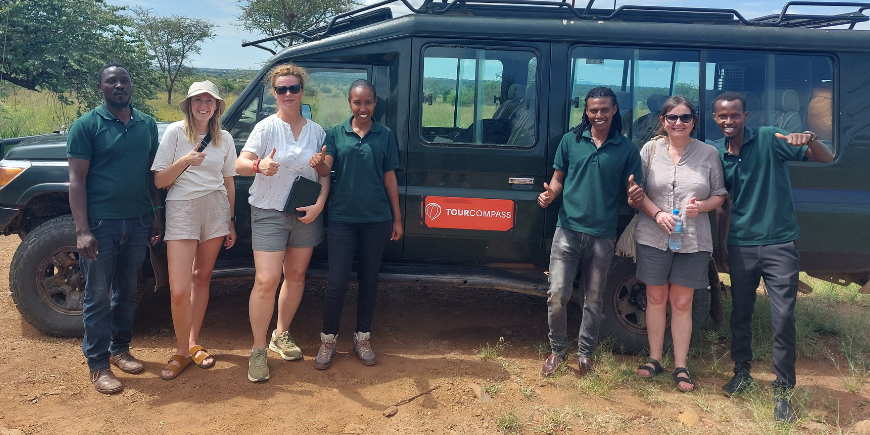 Safariresande och guider som står vid safaribil i Afrika