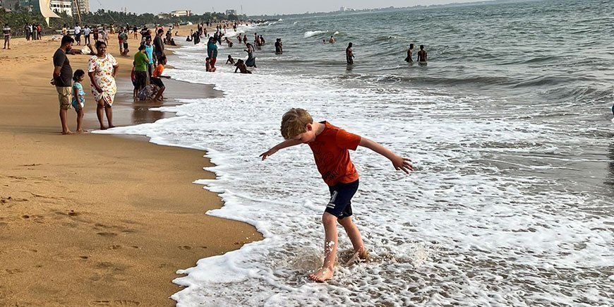 Pojke går i vattenkanten på gyllene strand på Sri Lanka
