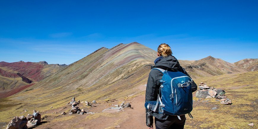 Kvinna går på regnbågsbergen i Peru