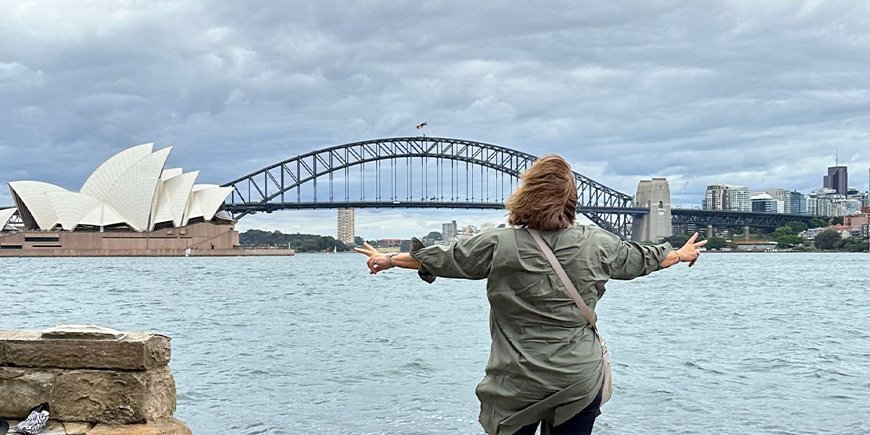 Beate står framför operahuset och Sydney Harbour Bridge i Australien