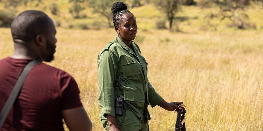 Kvinna står med gevär på savannen