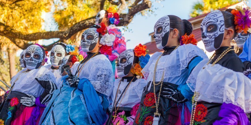 Kvinnor i färgglada dräkter med dekorerade dödskallar på De dödas dag i Mexiko