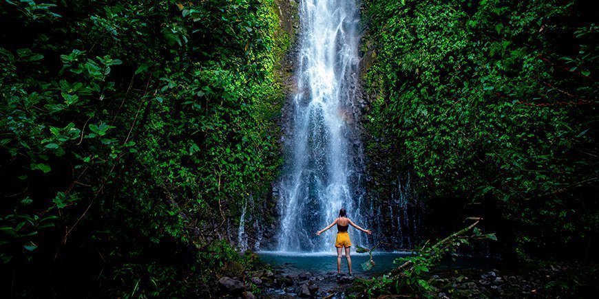Kvinna står framför ett vattenfall i Costa Rica