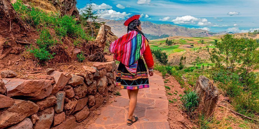 Kvinna från ursprungsbefolkning går längs en inkamur i Cusco i oktober