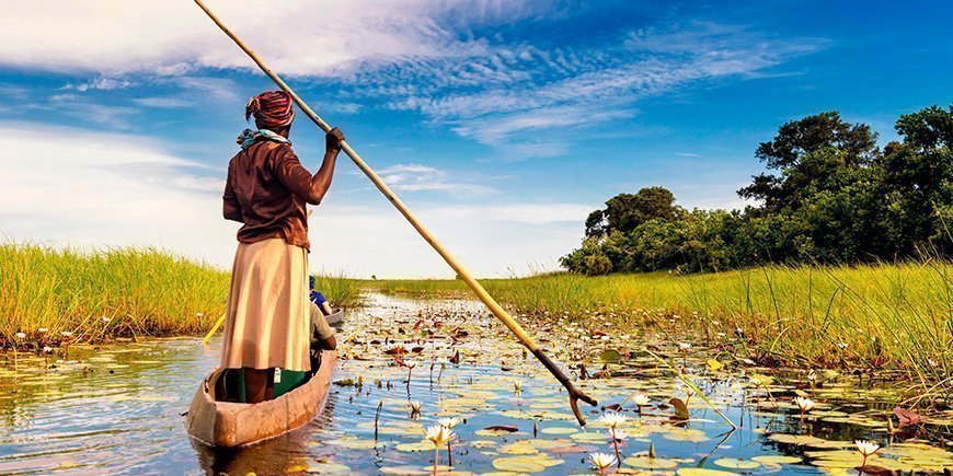 Kvinna seglar i en båt i Okavangodeltat i Botswana