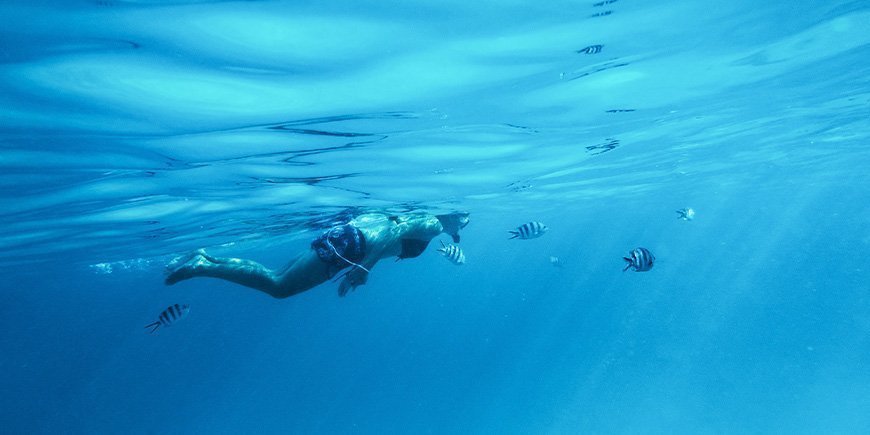 Kvinna snorklar under vattnet i Zanzibar