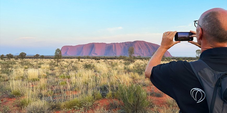 Man tar mobilfoto av Uluru i Australien