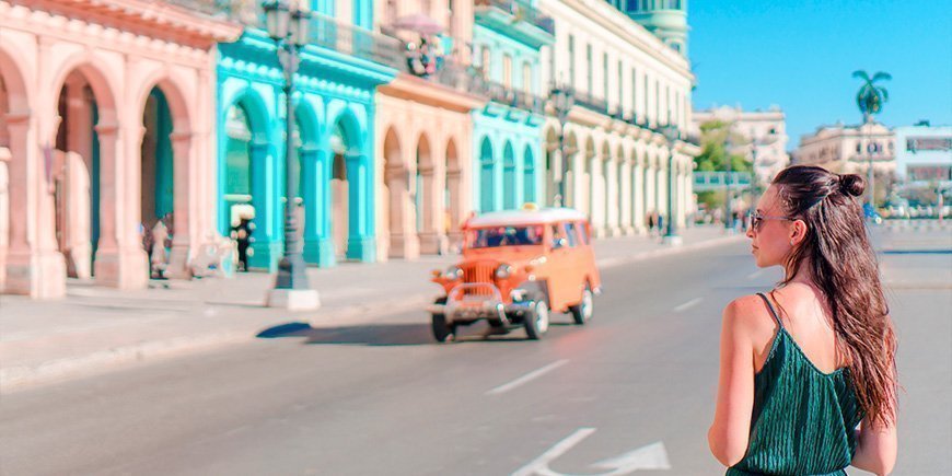 Kvinna promenerar på gator med färgglada byggnader i Havanna, Kuba