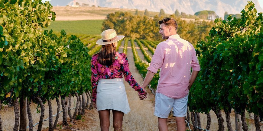 Kvinna och man håller varandra i handen på en vingård i Sydafrika