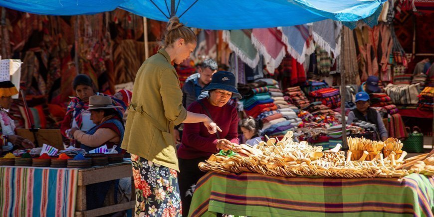 Kvinna köper lokala souvenirer i Cusco, Peru