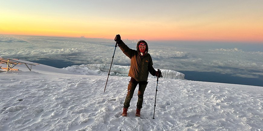 Kvinna står i snön på toppen av Kilimanjaro.