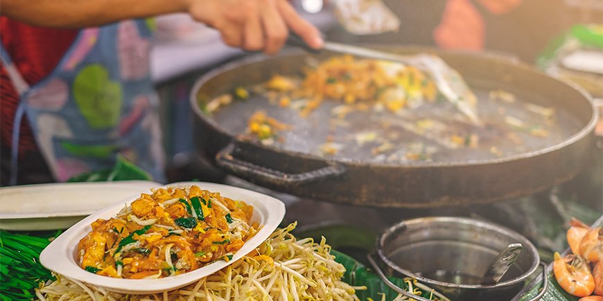 Kvinna gör Pad Thai på en marknad i Bangkok
