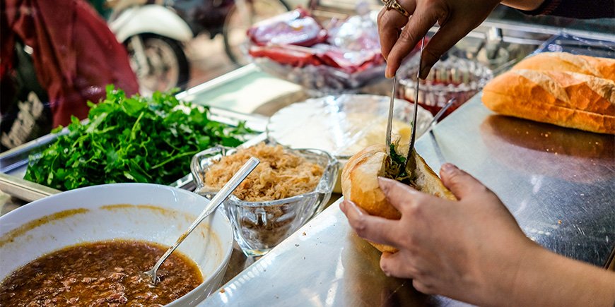 Kvinna gör en Banh Mi smörgås i Ho Chi Minh City, Vietnam