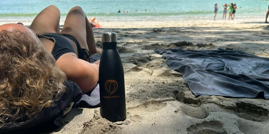 Kvinna ligger i sanden en solig dag på en strand i Costa Rica.