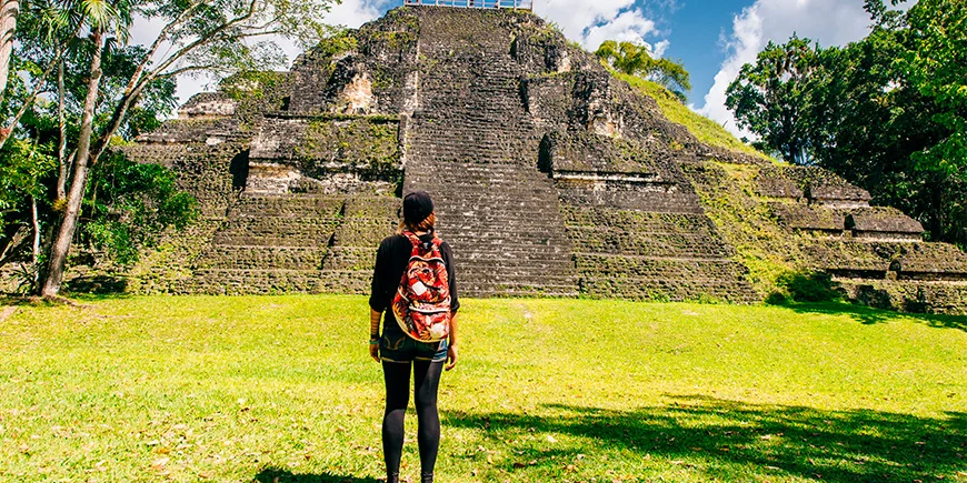 Kvinna står framför en pyramid i Tikal nationalpark 