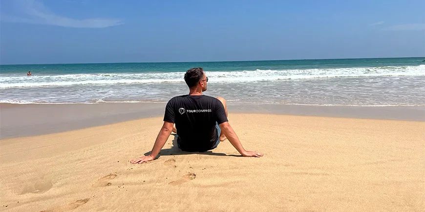 Man i TourCompass T-shirt sitter på stranden i Mirissa på Sri Lanka