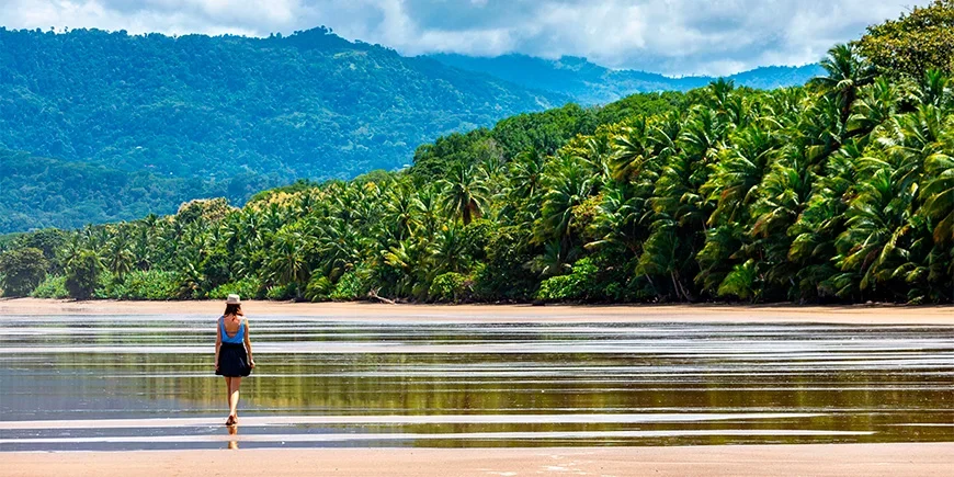 Kvinna promenerar vid vattnet på stranden Manuel Antonio i Costa Rica