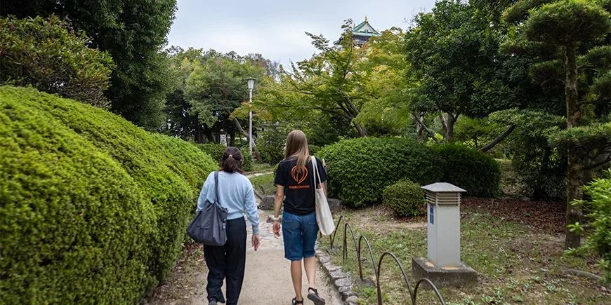 Japansk guide promenerar med en TourCompass-medarbetare vid Osaka Castle i Japan