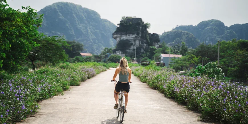 Kvinna cyklar på en stillsam väg i Ninh Binh i Vietnam