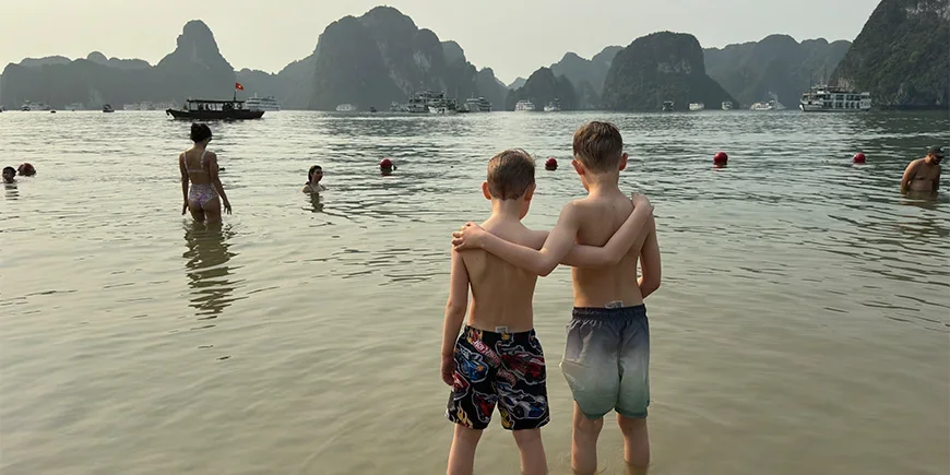 Två pojkar håller om varandra på en strand i Ha Long-bukten