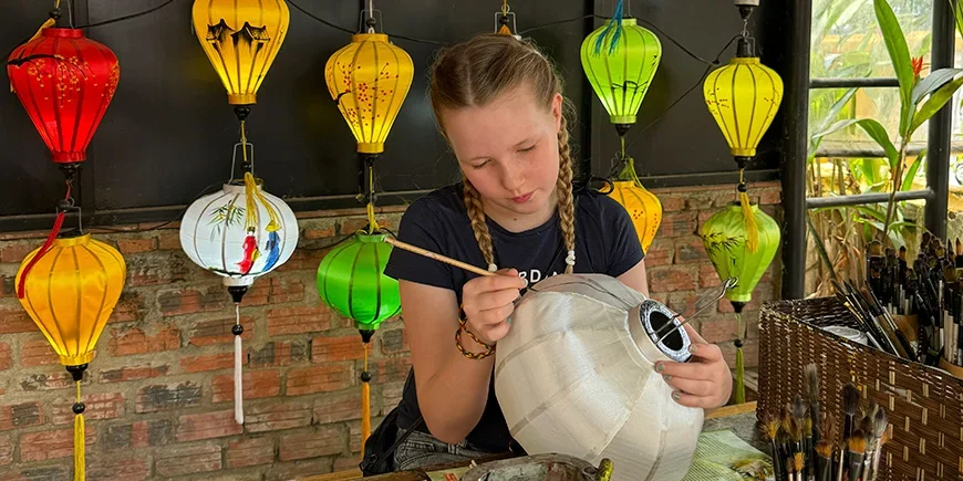 Flicka målar lyktor i Hoi An i Vietnam