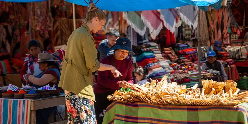 Kvinna pratar med en lokalinvånare om varorna hon säljer på en marknad i Cusco, Peru