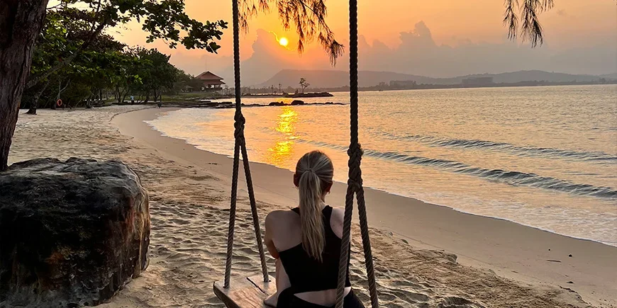 Flicka på gunga i solnedgången på stranden på Phu Quoc
