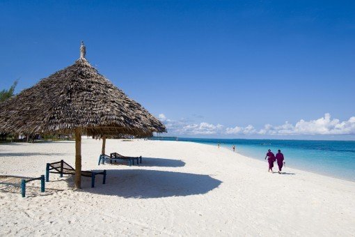 Lokalbor går i strandkanten på Zanzibar