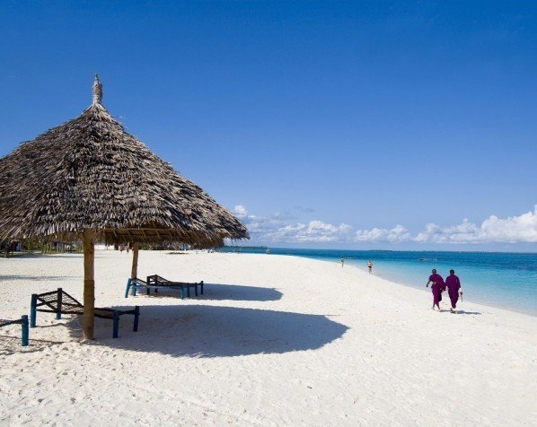 Lokalbor går i strandkanten på Zanzibar