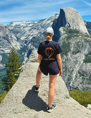 Kvinna i TourCompass-t-shirt på klippa i Yosemite